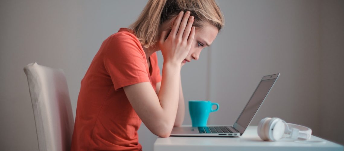 Young troubled woman using laptop at home